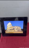 Front view of the digital photo frame showing the display with an image of the Colosseum.