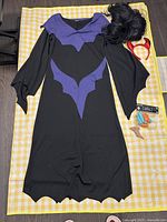 Full view of laid out witch costume dress and accessories on a yellow checkered surface.