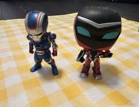 Photo showing two Marvel figures, Iron Patriot on the left and Rescue Funko Pop on the right, standing on a yellow and white checkered surface.