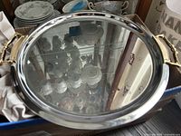 Top view of round metal tea tray showing reflective surface and gold-tone handles.