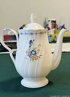 Front view of Nikko Japan porcelain bone china teapot with floral design on white ribbed body and curved handle.