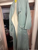 Light blue polyester bathrobe hanging open showing inside lining and pockets.