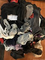 Photo of large pile of mixed socks in a bag showing different colors including black, grey, white, purple, and some patterned socks.