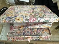 Open floral stationery box displaying layered items including patterned paper and envelopes inside