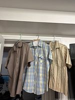 Three short sleeve shirts hanging side by side, showing colors and stripe patterns