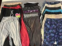 Photo showing the variety of pants and leggings folded and laid out, displaying multiple colors, patterns, and fabric types
