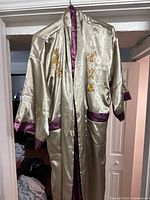 Gold side of the silky reversible robe with purple accents and golden pineapple embroidery visible on chest.