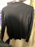 Back view of the plain black knit sweater without embroidery.