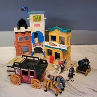 Full view of Fisher-Price Wild West town buildings, stagecoach with horses, cowboy figure, cannon carriage.