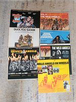 Photo showing six biker movie soundtrack vinyl record covers arranged on carpet. Titles visible include Devils Angels, Duck You Sucker, The Wild Angels Vol. II, Born Losers, Motions on the Speed, and Hells Angels on Wheels.