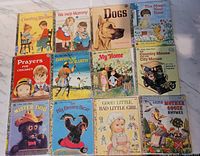 Photo showing 12 vintage Little Golden Books arranged in three rows. Titles visible include Counting Rhymes, We Help Mommy, Dogs, The Magic Next Door, Prayers for Children, David and Goliath, My Home, The Country Mouse and The City Mouse, Mister Dog, The Big Brown Bear, Good Little Bad Little Girl, and More Mother Goose Rhymes.
