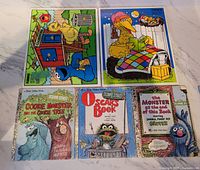 Photo showing two vintage Playskool Sesame Street board puzzles and three Little Golden Books featuring Cookie Monster, Oscar, and Grover.