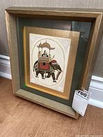 Framed Indian style art print of a richly decorated elephant with riders under a canopy, set in a light wood frame with beige and dark green matting.