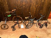 Front view of four metal and wood bicycles sculpture decor pieces on carpet with wooden background