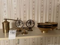 Shelves with brass decorative items including bowls, statues, a grinder, and a pedestal dish, showcasing their general appearance and grouping