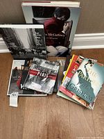 Photo showing assorted coffee table books stacked and fanned out on floor, featuring Paul McCartney, Linda McCartney, travel, and novels.