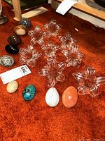 Overview photo showing the polished marble eggs and clear glass flower-shaped candle holders arranged on orange carpet.