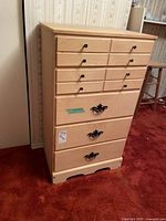 Full front image of high boy dresser showing 5 drawers with two styles of handles, light wood finish.