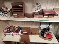 White plastic bin of foil rolls, wooden shelf organizer, multiple wooden boxes and machine in background