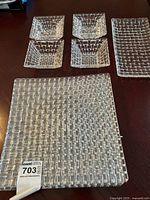 Top view of clear textured crystal glassware, including square plates, bowls, rectangular dish, and candle holders.