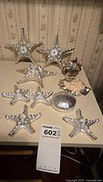 Seven silver-covered starfish and three silver-covered seashell decorative items on a table.