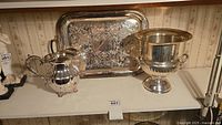 Photo showing the full set on a shelf: silverplate tray, silverplate pitcher, and silverplate ice bucket