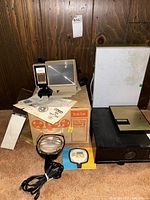 Lot showing all items including Batia slide projector with box, slide case, movie light, and slide viewer with manuals
