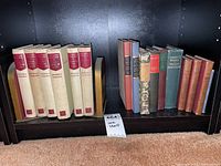 Books arranged on a shelf showing the full set of Winston Churchill's 'The Second World War' and additional older books including different sizes, colors, and bindings with bookends on each end.