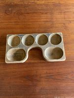 Top view of antique wooden cash register drawer insert, showing six round and two oval compartments with U-shaped cutout edge.