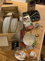 Cardboard box containing six place settings of IKEA Blond ceramic dinnerware plates and bowls.
