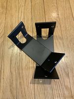 Single black metal bike hanger showing mounting plate, bent arm with cutout slot