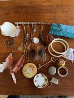 Top view of entire lot showing all items on wooden table including dreamcatchers, feathers, shell, plaques, plate, embroidery hoops, key, and small decorative objects.
