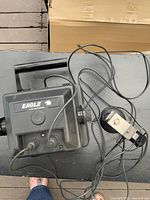 Black Eagle LCG depth finder device with cables and mounting bracket placed on a flat surface.