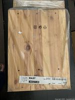 Close-up photo of IKEA RAST table wooden parts in clear plastic packaging showing label with dimensions and SKU.