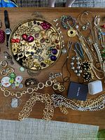 Overview of vintage costume jewelry and brass tray on wooden surface