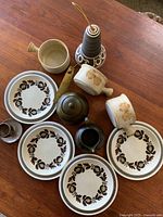 Photo showing 4 Stonehaven Sandra plates, 2 chipped soup bowls, a black and white patterned vase with brass spoon, dark green teapot, beige handled soup bowl, and Myott cream and sugar set.