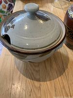 Studio pottery serving dish with lid, showing earthy glaze and ladle cutout