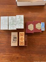 Nine boxed vintage Avon perfumes arranged on a table showing variety of box designs and sizes.