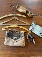 Wooden hangers marked with company names and locations, vintage purses, wooden shoe last and carved wooden block print blocks arranged on wooden surface