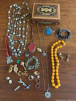 Overall view of the jewelry lot including music box and various jewelry pieces arranged on wood surface