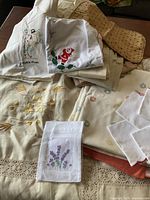 Collection of various vintage linens including embroidered pieces and pillowcases spread on a table.