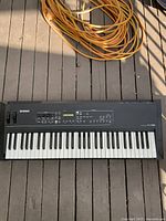 Top-down photo of Yamaha KX61 USB MIDI keyboard controller on wooden surface with yellow extension cord above.