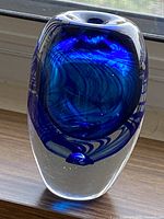 Clear image of vintage cobalt blue swirl glass vase showing rounded form and swirl pattern under natural light near window.