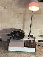 Side profile of the vintage Mid-Century Modern clock radio and adjustable lamp on countertop.