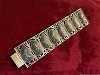 Full view of the vintage sterling silver Siam panel bracelet laid flat showing the series of black enamel panels with detailed dancer and god figures etched in gold-tone.