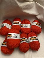 Eight skeins of bright orange vintage Parley Sport NIKRIM wool yarn arranged on a neutral background
