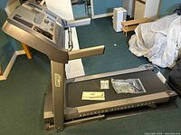 Full side-angle photo of full size treadmill with brand name on base and control panel visible