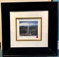 Framed artwork against wall, showing full composition and matting with gold inner frame and black outer frame.