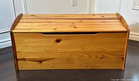 Front view of the solid pine wood blanket box with a curved cutout handle on the lid.