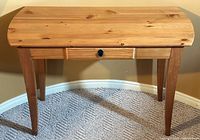 Photo of the full console table showing its natural wood grain texture and tapered legs on carpet.